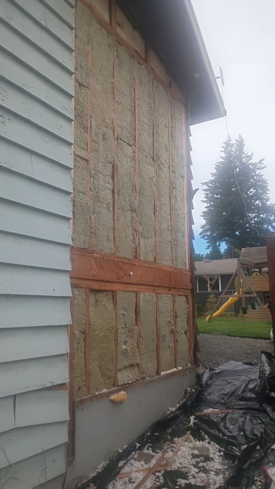 Exterior wall opened to studs and insulation during siding replacement